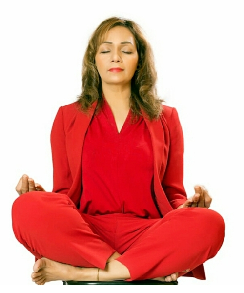 A woman doing  Sukhasana by seating in a relaxed cross legged pose with eyes close and breathing slowly.